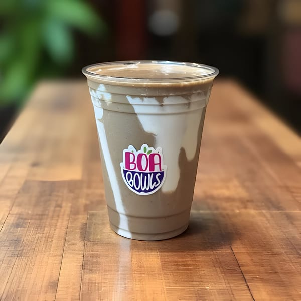 A Boa Bowls smoothie with white and brown swirls, featuring the brand logo, on a wooden table.